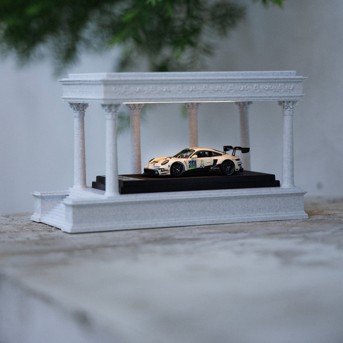 Model car on a white display stand with columns against a neutral background